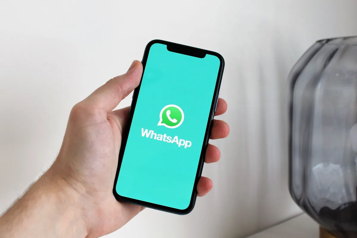 Smartphone screen showing a WhatsApp Business conversation with an automated greeting message responding instantly to a customer inquiry for a Malaysian service business