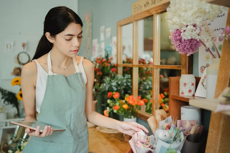 A woman business owner checks an order on a tablet in her shop