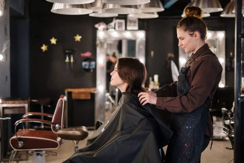 Stylist salon memberi perhatian penuh kepada pelanggan semasa sesi gunting rambut