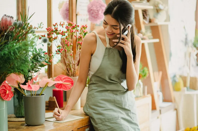 A happy small business owner smiles while checking their phone, representing the relief of having customer enquiries handled automatically