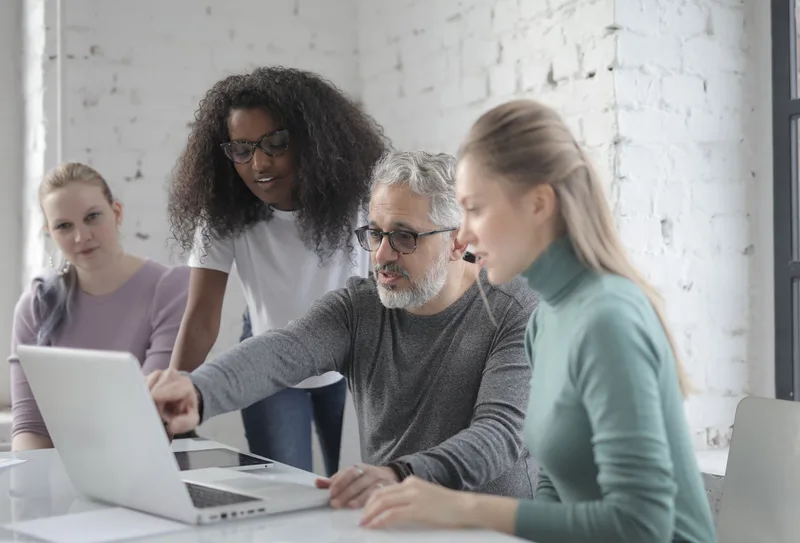 Team comparing software options on a laptop in an office meeting