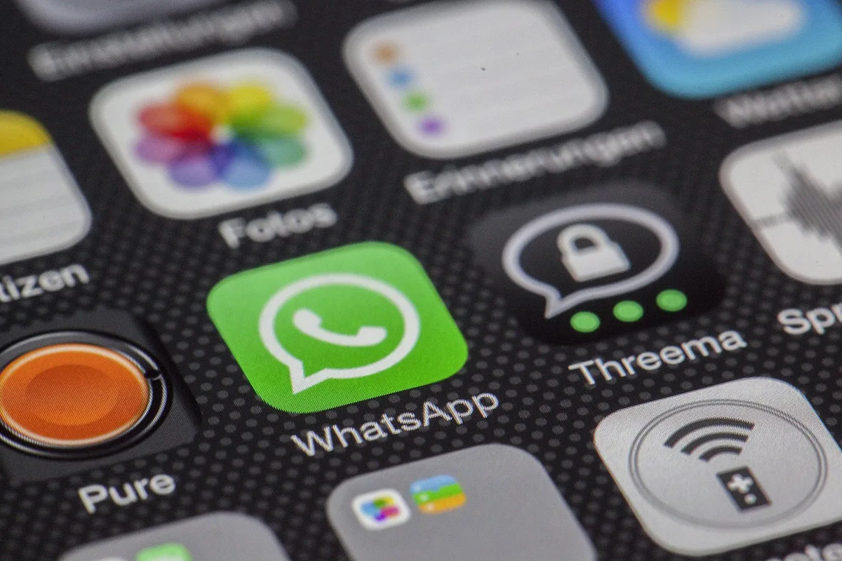 Smartphone showing a WhatsApp Business auto reply greeting message on screen, representing automated customer communication for Malaysian service businesses