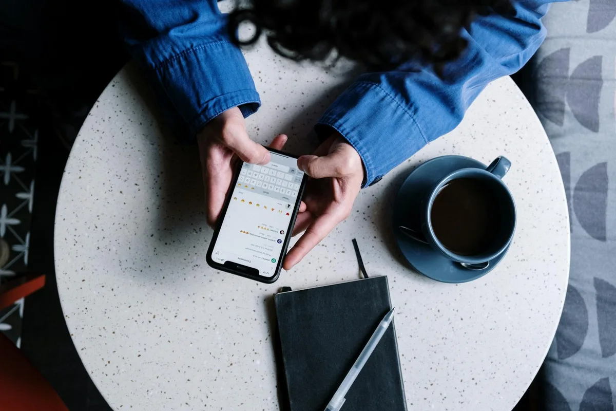 Business owner in Malaysia checking WhatsApp messages on a smartphone at a desk